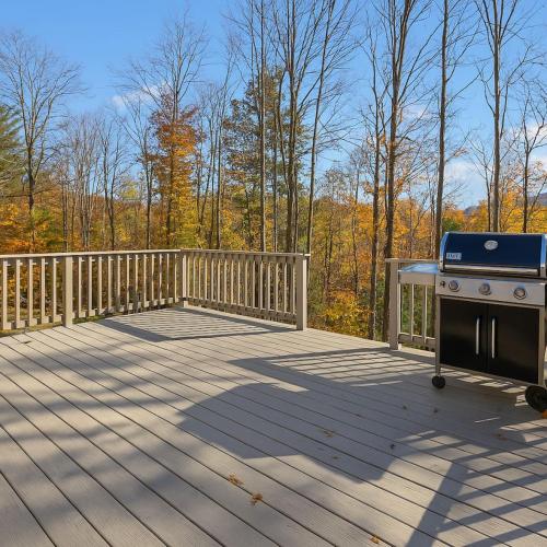 a grill on a wooden deck with trees in the background at Drift Haus 4 and half BR Mountain Lodge in Windham