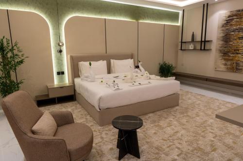 a bedroom with a large white bed and a chair at فندق لوكسري سويتس- Luxury Suites Hotel in Taif