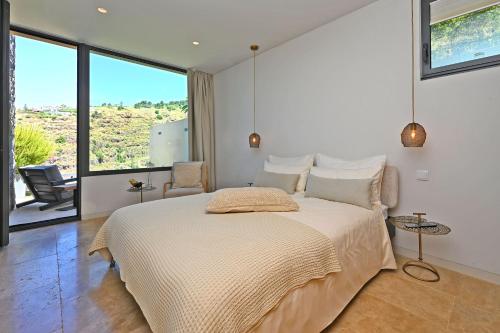 a bedroom with a large bed with a large window at The Rock Villas in Estreito da Calheta
