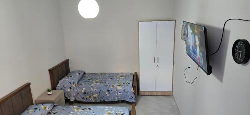 a bedroom with two beds and a tv on the wall at Adi's house in Tirana