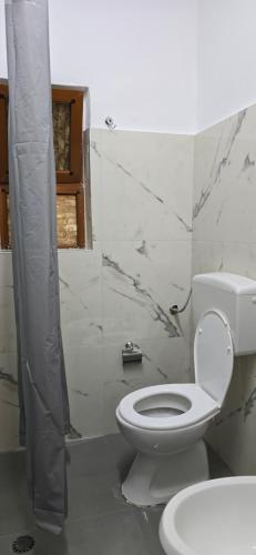a white bathroom with a toilet and a shower at Adi's house in Tirana