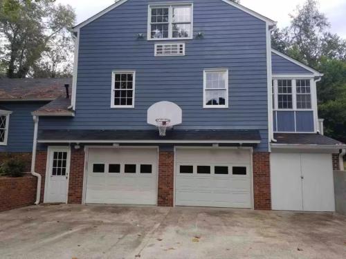 a blue house with two garage doors and a basketball hoop at Spacious Augusta Retreat Near Augusta National in Augusta