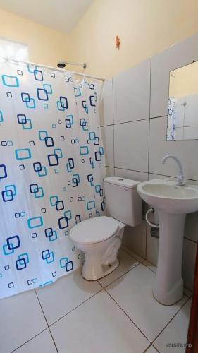 a bathroom with a toilet and a sink and a shower curtain at Refugio Kitesurf - ilha do Guajirú in Itarema