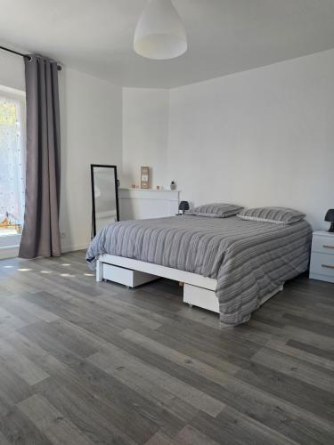 a white bedroom with a large bed and wooden floors at appartement Sedan, France in Sedan