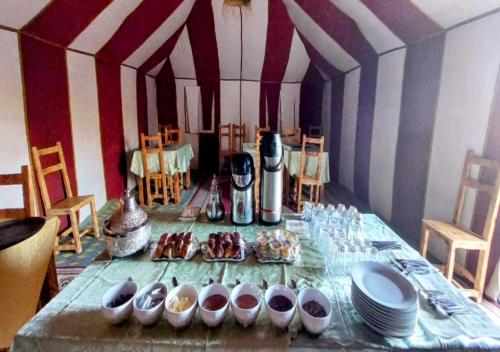 a table with plates and bowls of food on it at Merzouga Desert Tents in Merzouga
