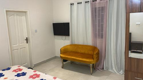 a bedroom with a chair and a bed and a television at Privée Cosy Moderne Equipée in Cotonou