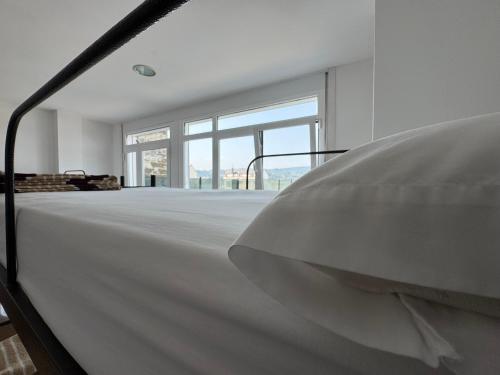 a white room with a bed and large windows at Albergue Internacional in Sarria