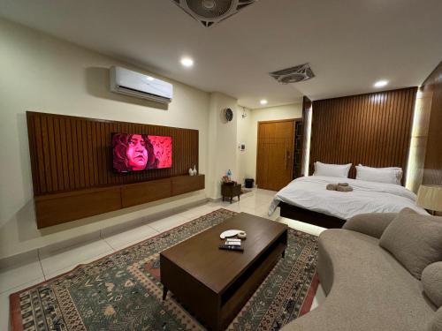 a bedroom with a bed and a tv on the wall at SkyLuxe Studio 2 with rooftop Pool & Self Check In in Islamabad