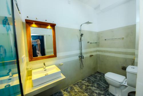 a bathroom with a sink and a toilet and a mirror at Camellia Unawatuna in Unawatuna
