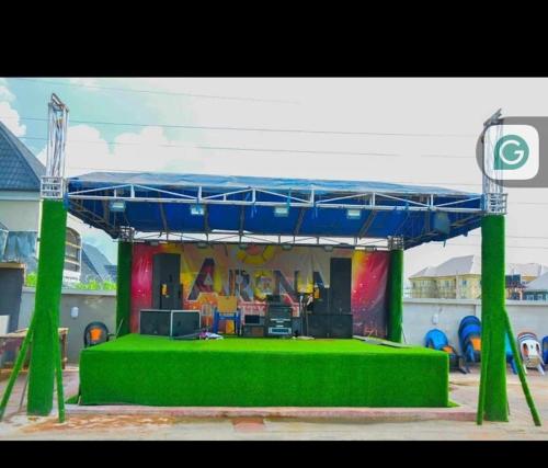 a stage with a green floor and a blue canopy at Ohio city hotel in Owerri