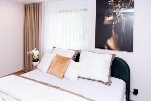 a bedroom with a white bed with white pillows at Apartamenty nad Starynką in Głuchołazy