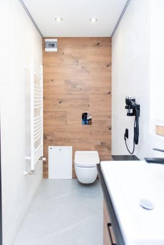 a bathroom with a toilet and a wooden wall at Apartamenty nad Starynką in Głuchołazy