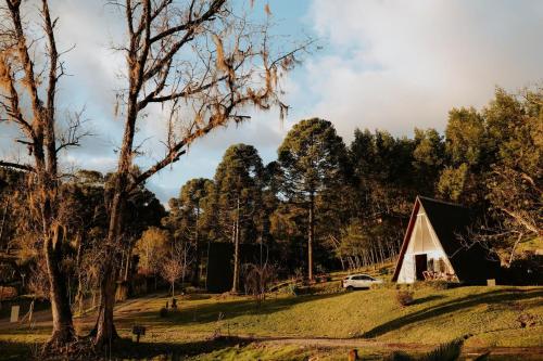 a barn on a hill with trees in the background at Cabana com banheira in Gramado