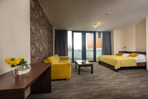 a hotel room with a bed and a yellow chair at Hotel Panorama Resort in Štrbské Pleso