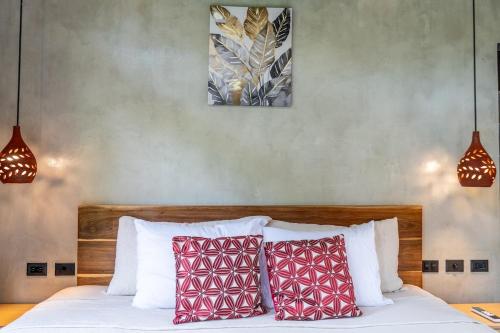 a bedroom with a bed with red and white pillows at Raya Bungalow, AC and Plunge Pool near Arrecife Beach in Punta Uva