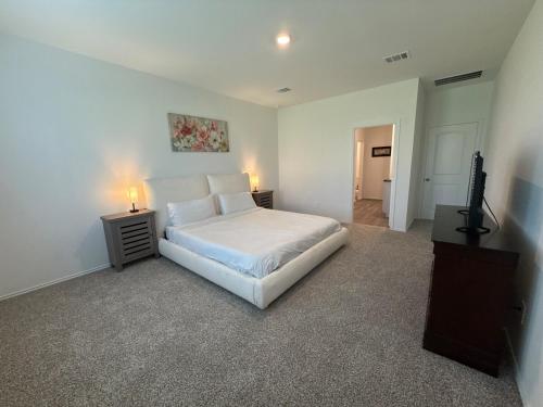 une chambre avec un lit blanc et une télévision dans l'établissement Cozy Magnolia 4BR 3BA Family Home Retreat, à Magnolia