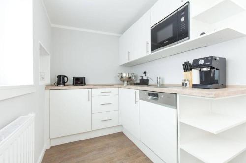 a white kitchen with white cabinets and a microwave at ChillingHouse Apartments Siegburg in Siegburg