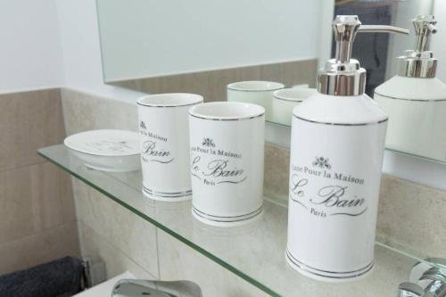 a glass shelf with four bottles on it in a bathroom at ChillingHouse Apartments Siegburg in Siegburg
