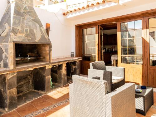 ein Wohnzimmer mit einem Steinkamin und Stühlen in der Unterkunft Live Caletillas Taunus pool in Punta Larga