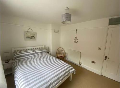 a white bedroom with a bed with a striped comforter at Bimble Cottage-2 beds-Gorgeous Sunny Garden in Topsham