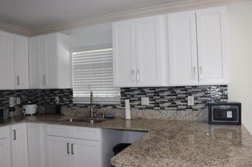 a kitchen with white cabinets and a sink at Super Room 5 minutes from PBI Airport in West Palm Beach