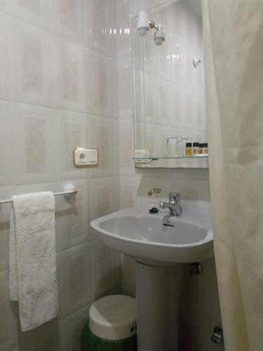 a bathroom with a sink and a toilet and a mirror at Hostal Villa María in La Nava de Ricomalillo