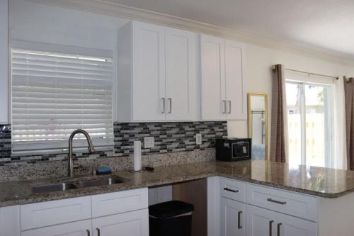 a kitchen with white cabinets and a sink and a microwave at Super Room 5 minutes from PBI Airport in West Palm Beach