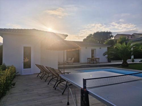 a patio with a table with chairs and an umbrella at Logement indépendant avec piscine privée in Penta-di-Casinca