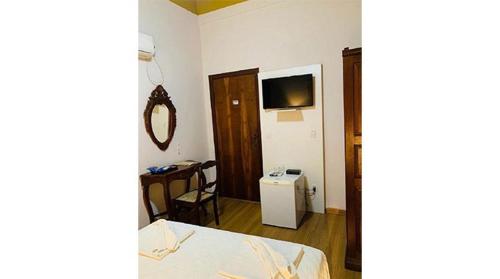 a room with a bed and a table and a television at Hotel Lenheiros in São João del Rei