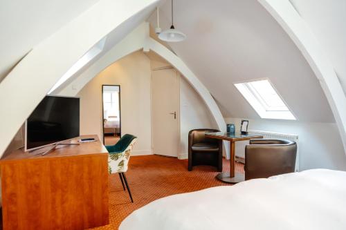 a bedroom with a bed and a desk and a tv at Ambassador City Centre Hotel in Haarlem