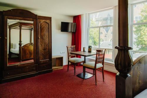 a bedroom with a table and chairs and a mirror at Ambassador City Centre Hotel in Haarlem
