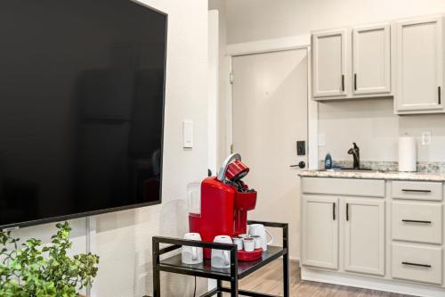 a kitchen with white cabinets and a tv and a table at Downtown One Bedroom Apartment Fully Furnished in Great Falls