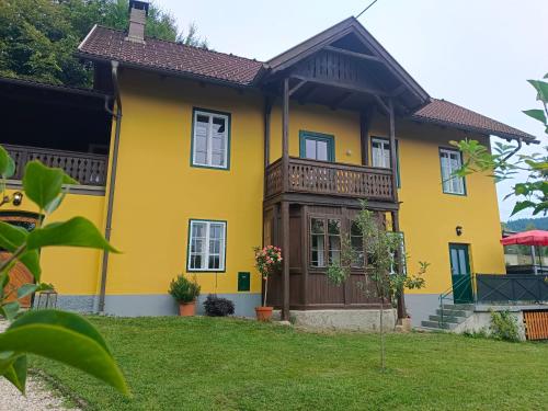 a yellow house with a balcony at Ferienwohnungen Villa Winkler in Velden am Wörthersee
