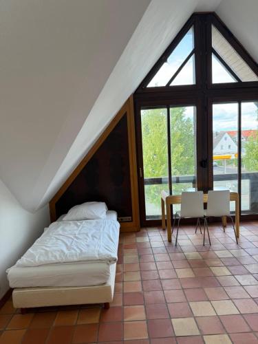 a bedroom with a bed and a table and a window at Hotel Hessler-Veranda in Maintal