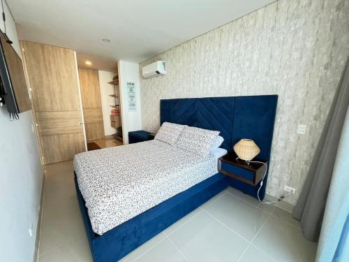 a bedroom with a bed with a blue head board at Reserva Del Mar Apartamentos in Gaira