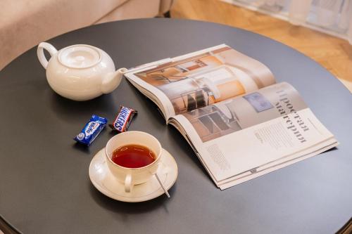 a table with a book and a cup of tea and a tea pot at Luxe Apartment 18-th floor and sky view in Tashkent City NRG U-Tower in Tashkent