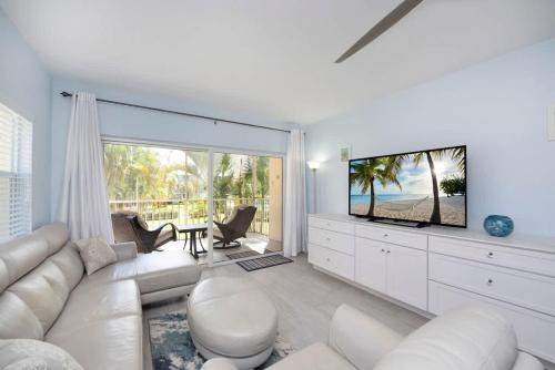 a living room with a white couch and a television at Plantation Village #37 Condo in Seven Mile Beach