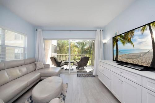 a living room with a couch and a large screen tv at Plantation Village #37 Condo in Seven Mile Beach