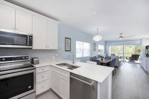 a kitchen with white cabinets and a dining room at Plantation Village #37 Condo in Seven Mile Beach