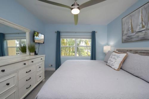 a bedroom with a white bed and a ceiling fan at Plantation Village #37 Condo in Seven Mile Beach