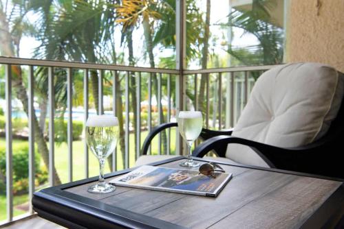 a wooden table with two wine glasses and a magazine at Plantation Village #37 Condo in Seven Mile Beach