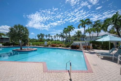 a swimming pool with palm trees and a blue sky at Plantation Village #37 Condo in Seven Mile Beach