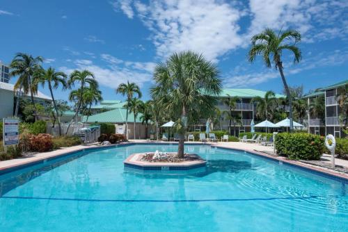 a large swimming pool with palm trees in a resort at Plantation Village #37 Condo in Seven Mile Beach