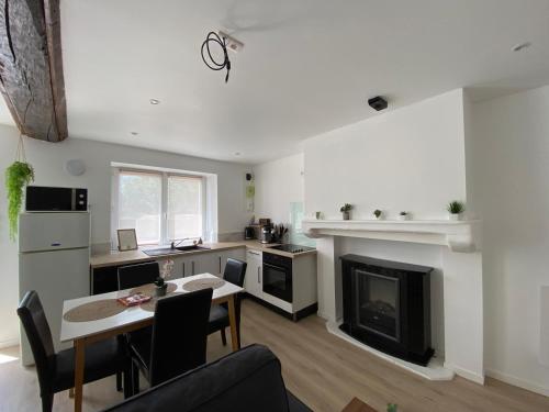 a living room with a table and a fireplace at Petite maison de bourg in Le Bourgneuf-la-Forêt