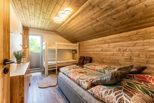 Dos camas en una habitación con paredes de madera. en Chalet SiSa, en Ižipovce
