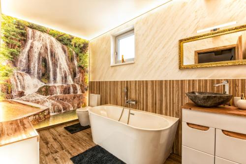 Un baño con bañera y un mural de cascada. en Chalet SiSa, en Ižipovce