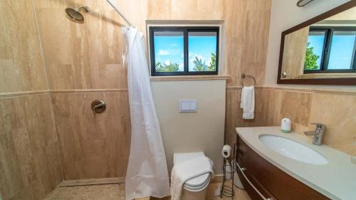 a bathroom with a shower and a sink and a toilet at Seven Mile View Condo #1 in West Bay