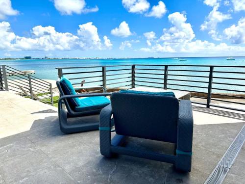 two chairs sitting on a deck near the water at Seven Mile View Condo #1 in West Bay