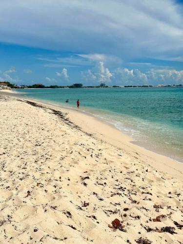 a sandy beach with people swimming in the ocean at Seven Mile View Condo #1 in West Bay