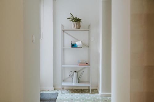 a white shelf in a hallway with a plant on it at S. Pedro 27 in Sintra
